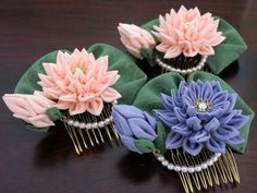 three hair combs with flowers on them sitting on a wooden table next to each other