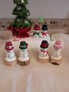 a group of snowmen sitting next to a christmas tree on top of a table