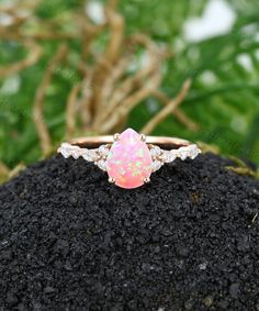 an opal and diamond ring on top of a rock