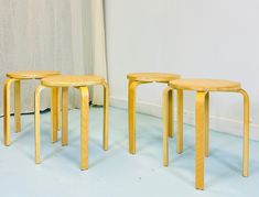 three wooden stools sitting next to each other in front of a curtained window