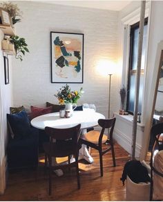 a white table and chairs in a small room with wood flooring next to a window