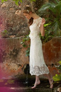 a woman in a white dress standing next to a fountain