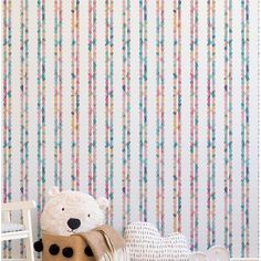 a teddy bear sitting on top of a wooden floor next to a wall with colorful stripes