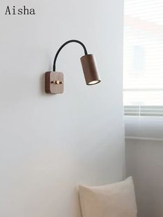 a wall light that is on the side of a wall next to a chair and window