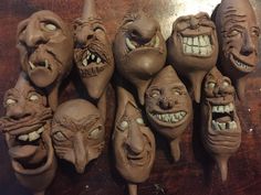 several clay masks with faces and mouths are arranged in a row on a wooden surface