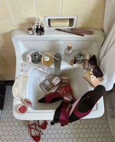 a bathroom sink filled with lots of personal care items and makeup on top of it