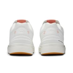 a pair of white sneakers with orange soles on top of the shoe and side view