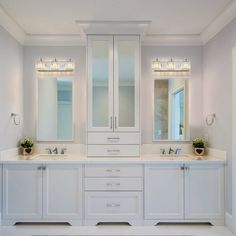 a white bathroom with double sinks and two large mirrors on the wall above them is shown