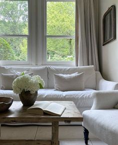 a living room filled with furniture and a window covered in white curtained drapes