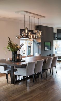 a dining room table and chairs with lights hanging from the ceiling