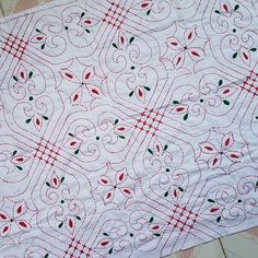 a white table cloth with red and green designs on it, sitting on a tile floor