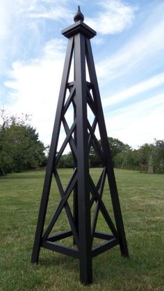 a large metal clock tower in the middle of a field