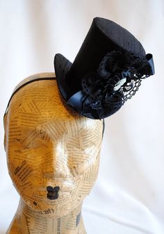 This victorian goth mini top hat is a simple yet elegant piece.It is covered with black silk shantung and adorned with black satin ribbon in a vertical half bow, vintage black cotton lace in a rosette, pleated satin ribbon, which forms an oval frame for a beautiful black and white victorian profile cameo. Choose between with or without black veil. Also available in a white and black combination: https://www.etsy.com/bizarrenoir/listing/166826619/gothic-mini-top-hat-in-purple-velvet?ref=shop_home Small Top Hat, British Hats, First Birthday Hats, Black Combination, Mad Hatter Hat, Mini Crown, White Victorian, Black Top Hat, Millinery Supplies