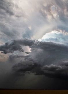 an airplane is flying in the sky with dark clouds behind it and sunbeams