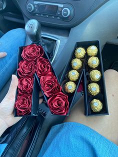 someone is holding roses and chocolates in their car