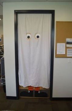 an open door with two fake eyes on it and a white sheet covering the doorway