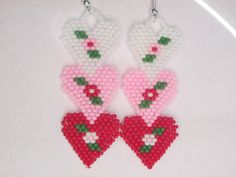 two heart shaped beaded earrings hanging on a hook