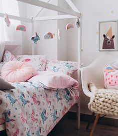 a child's bedroom with pink and white bedding, unicorns on the wall