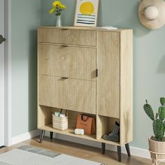 a wooden cabinet sitting in the corner of a room next to a potted plant