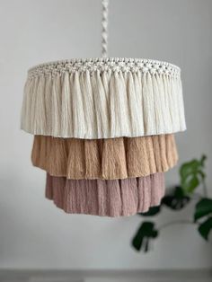 a white and pink chandelier hanging from a ceiling with tassels on it