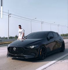 a man standing on the hood of a black sports car