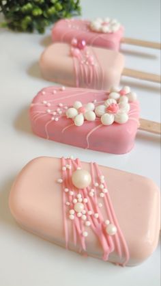 three pink and white cake pops sitting on top of a table