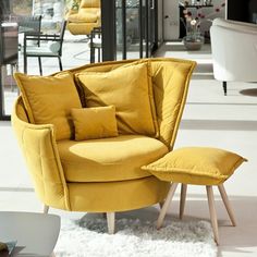 a yellow chair and ottoman in a living room with white rugs on the floor