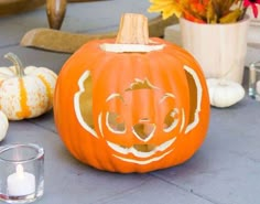 an orange pumpkin sitting on top of a table next to two candles and some flowers