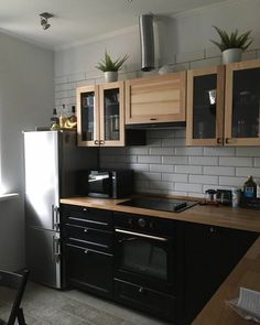 a kitchen with wooden cabinets and black appliances on the counter top, along with a white brick wall