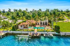 an aerial view of a house and dock in the water with palm trees around it