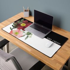 a laptop computer sitting on top of a wooden desk next to a mouse pad and pen