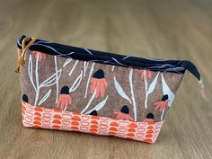 an orange and brown flowered pouch sitting on top of a wooden table