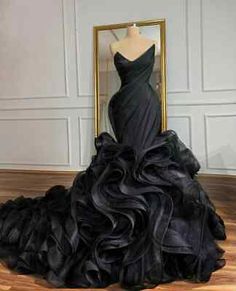 a black dress sitting on top of a wooden floor next to a framed photo in a room