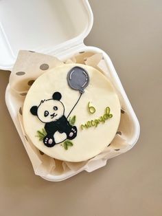 a panda bear cake in a foam container with a balloon on the top and writing happy 6th birthday