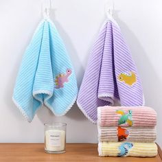 two towels hanging on the wall next to a candle