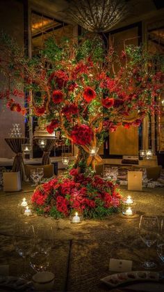 a table with candles and flowers on it in a room filled with tables, chairs and chandeliers