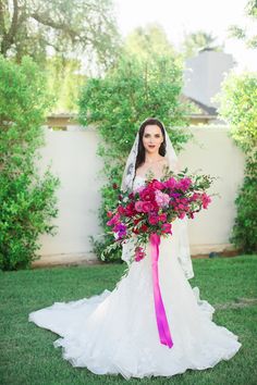 a woman in a wedding dress holding a bouquet and posing for the camera on her wedding day