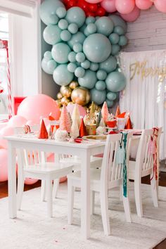 a white table topped with lots of pink and blue balloons