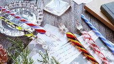 three colorful candles are sitting on top of an open letter and some pine branches next to it