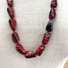 Red, Black and White Hand Knotted Graduated Glass Bead Necklace featuring an unusual necklace comprising 37 unique hand made tetrahedral or humbug shaped parcel graduated glass beads with varying tones of deep red, black and white with varying degrees of visible stripes.  This wonderfully tactile necklace is hand knotted with a deep red cotton thread, it has a screw clasp is 75cm long and weighs 105.2g. This beautiful piece of jewellery began its journey many years ago and may have some very min Unique Red Agate Beaded Necklaces, Artisan Red Agate Beads, Handmade Red Agate Necklace, Rectangular Beaded Necklace With Large Beads For Gifts, Unique Red Agate Necklaces, Unique Red Beaded Necklace With Faceted Beads, Unique Red Agate Necklace, Red Glass Beaded Necklace With Large Beads, Red Czech Glass Beaded Necklaces As A Gift