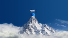 a mountain covered in clouds with a water bottle on it's top that says nestle