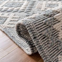 a close up view of a rug on the floor with wood floors in the background