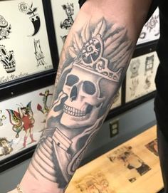 a man's arm with a skull wearing a crown tattoo on the left forearm