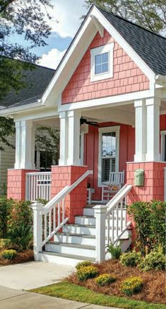 a pink house with white trim on the front porch