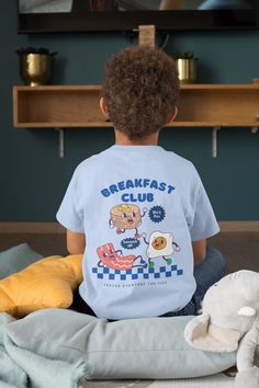 Breakfast Club Toddler Tshirt, Kids Retro Vintage Tshirt. This T-shirt is 100% Cotton and has a 2-Part design on the front and back featuring pancakes, bacon and eggs! Order a size or two up for an Oversized look. For the adult sizes please check out: https://www.etsy.com/uk/listing/1674601835/breakfast-club-aesthetic-bohemian-retro NOTE TO OUR CUSTOMERS We are a new business and very much appreciate your support! If you love your Tee as much as we hope you do, please leave us a review, thank yo Cute Cartoon Print T-shirt, Playful Cartoon Print Crew Neck T-shirt, Playful Crew Neck T-shirt With Cartoon Print, Playful Unisex Pre-shrunk T-shirt, Playful Cotton T-shirt With Front Print, Graphic Tee With Cartoon Print For All Genders, Blue Family Matching T-shirt With Cartoon Print, Family Matching Blue T-shirt With Cartoon Print, Family Matching Cotton Graphic T-shirt