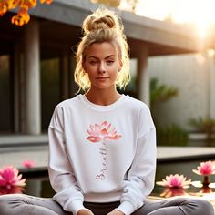 Find your center with our "Breathe" Sweatshirt, showcasing a graceful lotus flower with a unique twist--its stem beautifully spells out the word "breathe." The minimalist design, inspired by mindfulness and serenity, is perfect for those who seek balance and calm in their daily lives. The soft lines of the lotus flower, combined with the meaningful message, create a wearable reminder to pause and connect with your inner peace. Ideal for yoga lovers, meditation enthusiasts, or anyone who values m Casual White Top For Meditation, White Crew Neck Top For Meditation, White Crew Neck Top For Relaxation, Relaxed Fit Graphic Print Tops For Meditation, White Relaxed Fit Yoga T-shirt, White Relaxed Fit T-shirt For Yoga, Inspirational Tees, Meaningful Messages, The Lotus