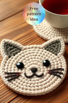 a crocheted cat coaster next to a cup of tea