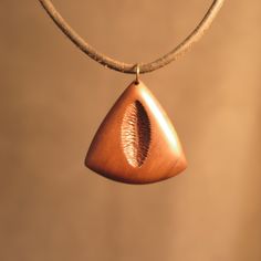 a wooden necklace with a tear shaped pendant hanging from it's leather cord on a brown background