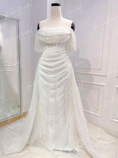 a white wedding dress on display in front of a mirror