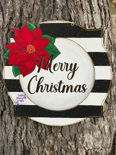 a merry christmas sign on a tree with a poinsettie hanging from it